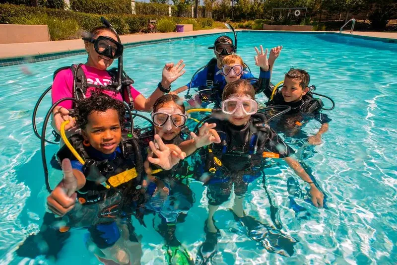 Groupe d'enfants souriants en équipement de plongée dans une piscine