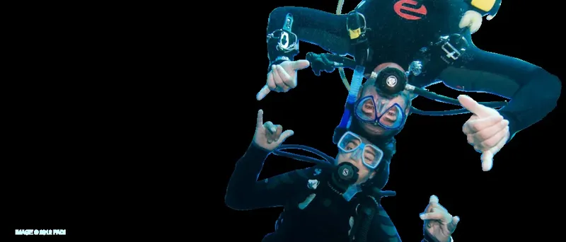 Deux plongeurs souriants font des signes de la main sous l'eau