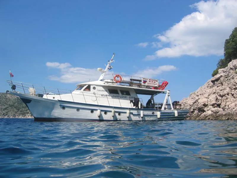 Grand bateau blanc amarré dans une crique rocheuse ensoleillée