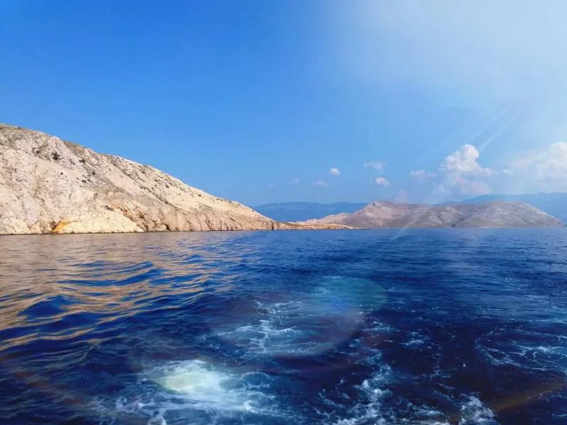 Vue mer depuis un bateau, côte rocheuse et ciel bleu clair