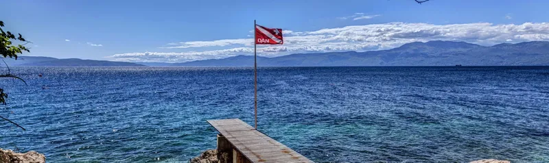 Drapeau de plongée flottant au-dessus d'une mer bleue et d'un quai
