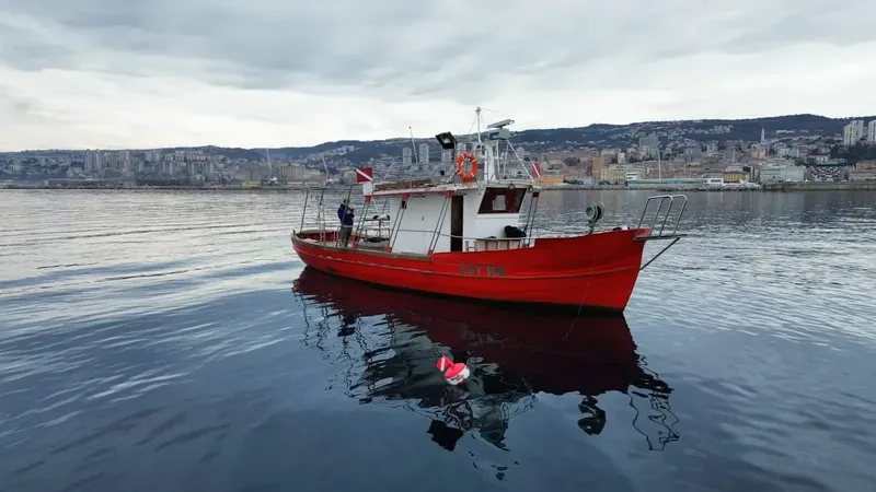Bateau de plongée rouge amarré dans un port avec des personnes à bord
