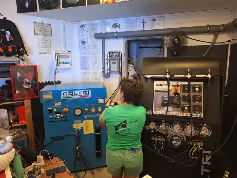 Une personne travaille sur un compresseur de plongée dans un atelier