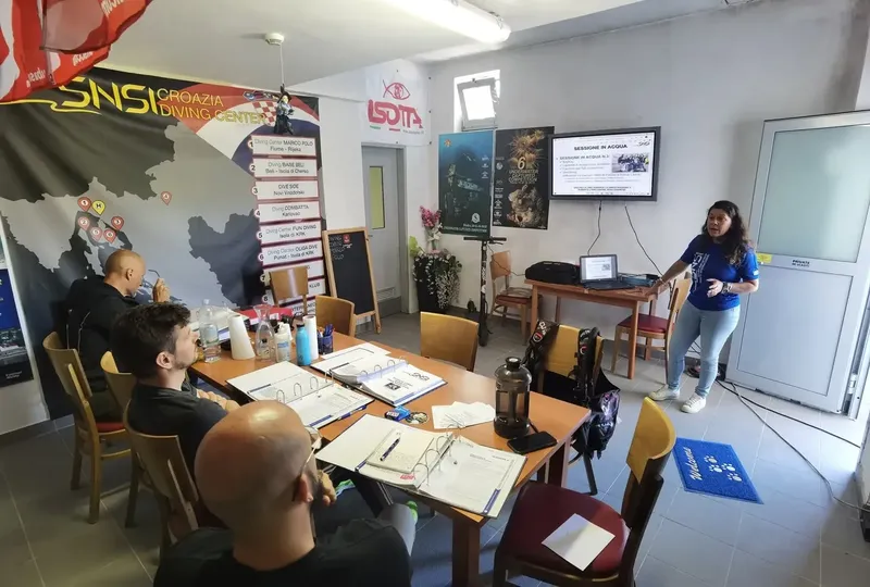 Cours de plongée en salle avec instructeur et participants attentifs