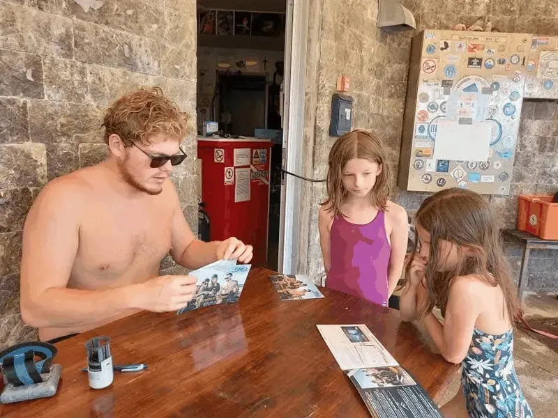 Deux enfants et un homme regardent des documents sur une table