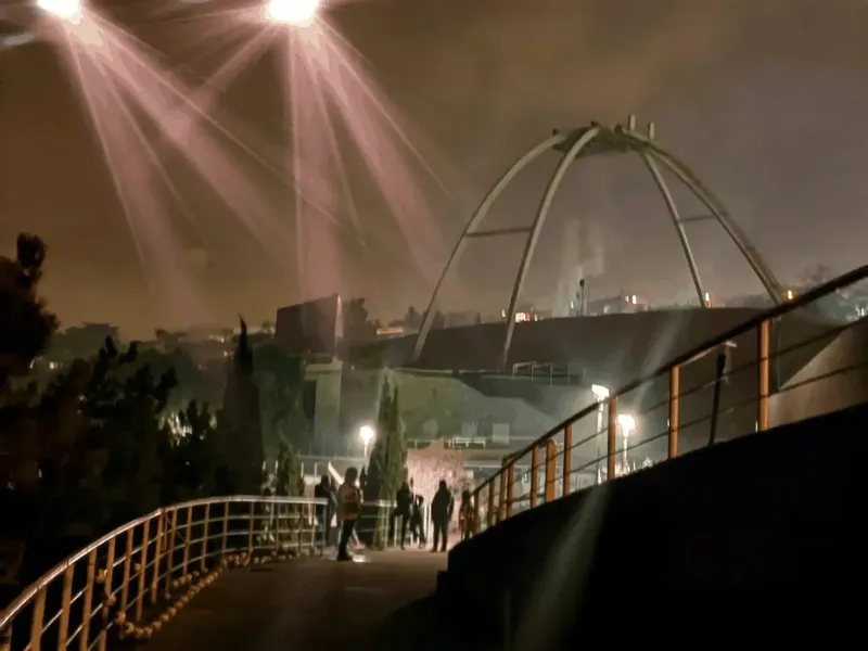 Vue nocturne d'un centre avec des personnes sur une passerelle éclairée