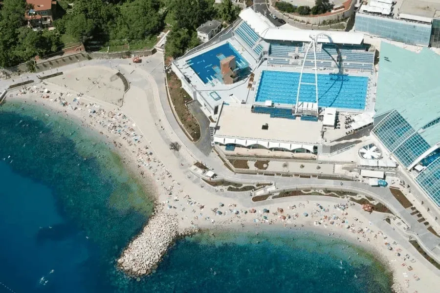Vue aérienne d'une piscine et d'une plage ensoleillée avec des baigneurs
