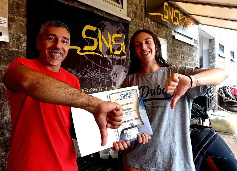 Deux personnes souriantes présentent un certificat de plongée Open Water