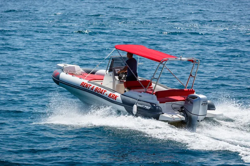 Bateau semi-rigide rouge et blanc navigue sur une mer bleue ensoleillée