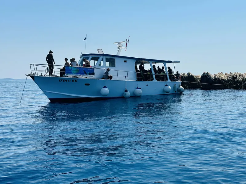 Bateau de plongée blanc avec des passagers, mer bleue et ciel clair