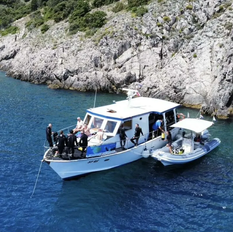 Bateau de plongée avec des personnes équipées en combinaison sur le pont