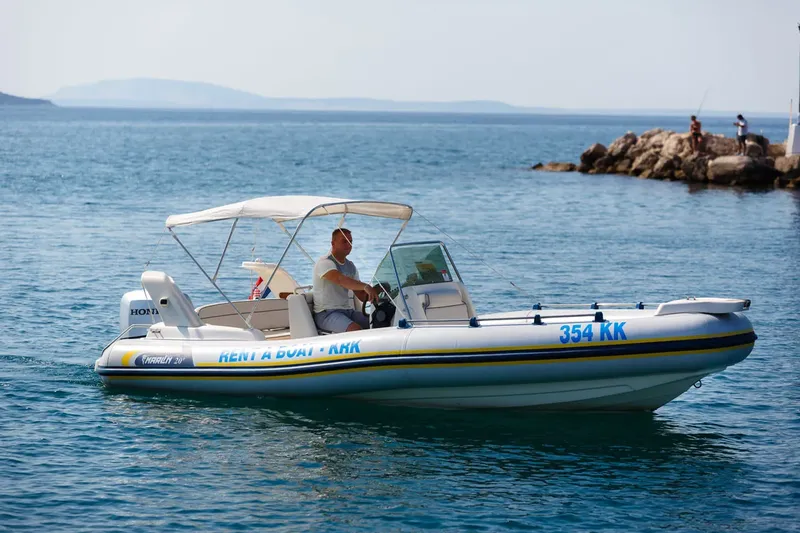 Homme conduisant un bateau pneumatique blanc et bleu en mer
