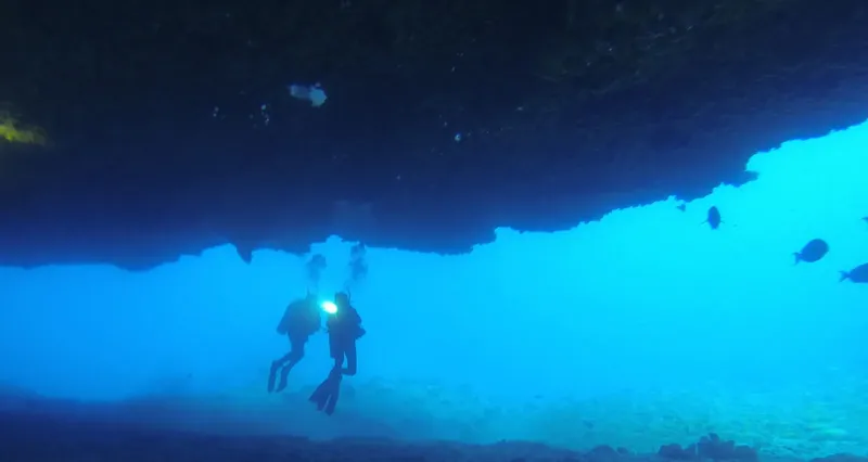 Deux plongeurs explorent une grotte sous-marine éclairée par leurs lampes