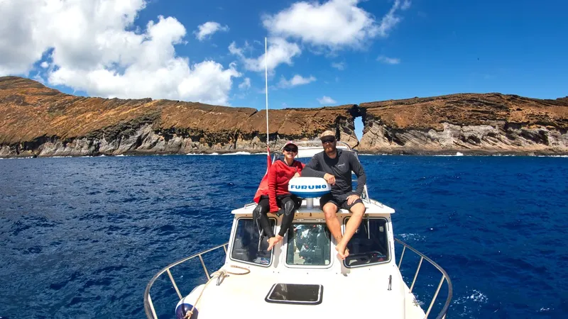 Deux plongeurs souriants assis sur la proue d'un bateau en mer