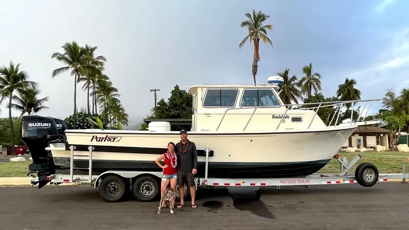 Couple souriant posant fièrement devant un bateau de pêche sur remorque