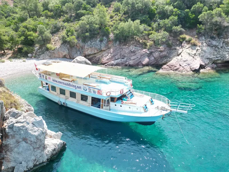 Bateau de plongée blanc et bleu amarré dans une crique turquoise