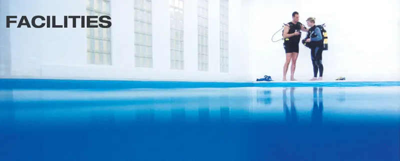 Deux plongeurs équipés près d'une piscine, préparation à la plongée
