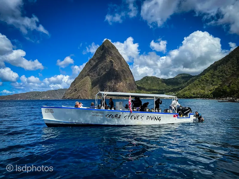 Bateau de plongée avec des plongeurs en mer, montagne en arrière-plan