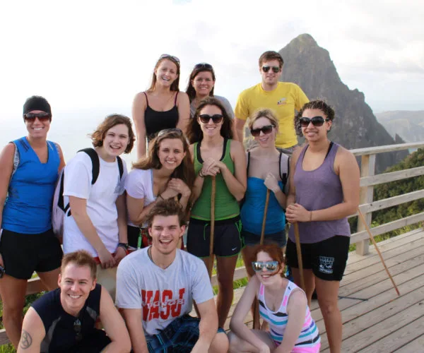 Groupe de personnes souriantes posant devant un paysage montagneux côtier
