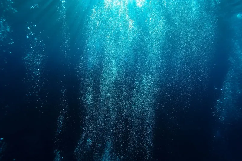 Bulles remontant vers la surface dans l'eau bleue et sombre
