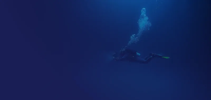 Plongeur en combinaison noire nageant vers le haut dans l'eau bleue