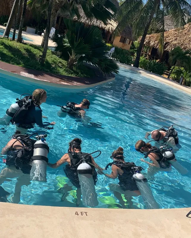 Groupe de plongeurs en formation dans une piscine turquoise ensoleillée
