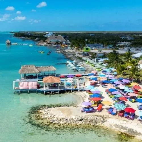 Plage tropicale avec ponton, transats colorés et bateaux amarrés