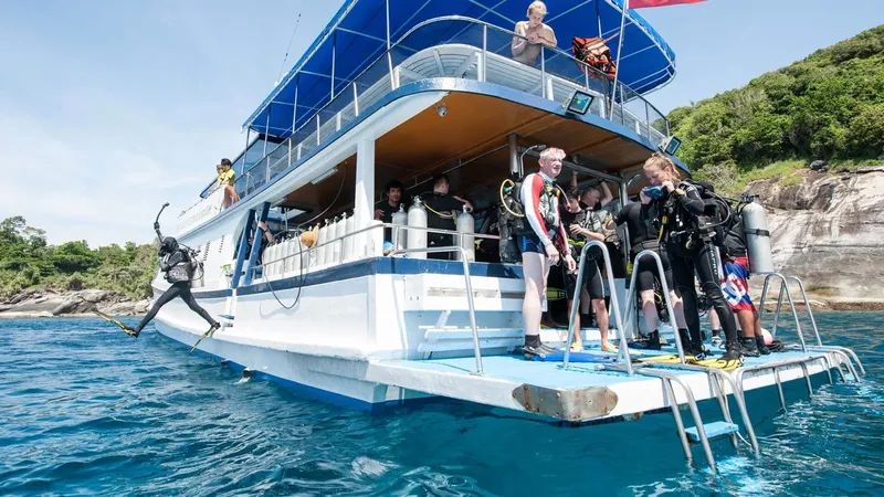 Plongeurs se préparent à sauter d'un bateau blanc en mer