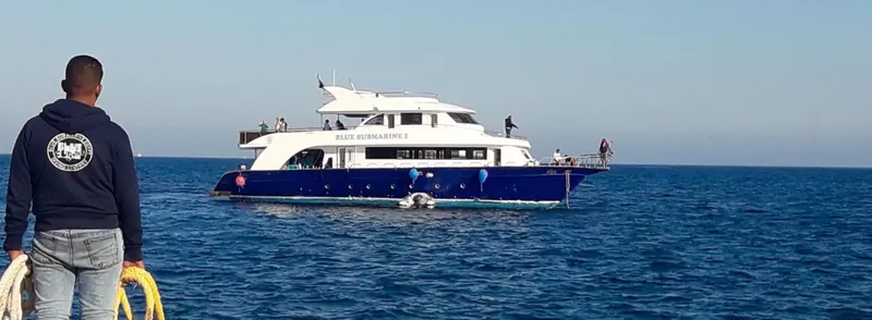 Homme regardant un grand bateau de plongée bleu sur mer calme