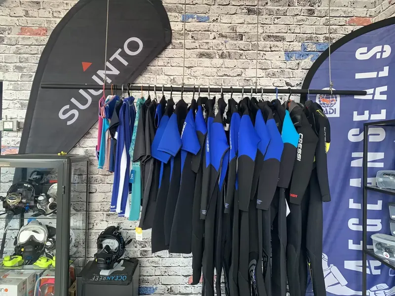 Combinaisons de plongée noires et bleues suspendues dans un magasin de plongée
