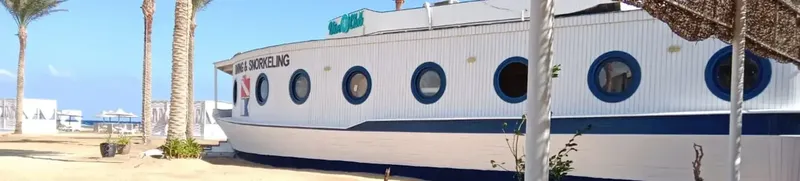 Bateau blanc et bleu amarré sur une plage de sable clair