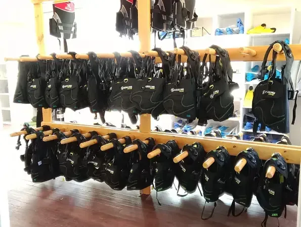 Rangées de gilets de sauvetage noirs suspendus dans un local de plongée