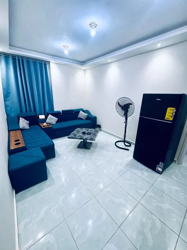 Interieur d'une piece avec canape bleu, table basse et refrigerateur