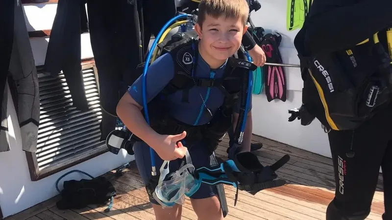 Jeune plongeur souriant avec son équipement sur un bateau