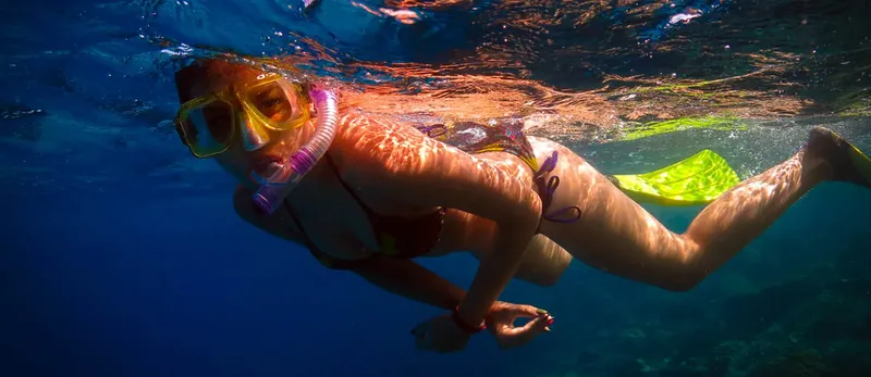 Plongeuse avec masque et tuba nageant dans une eau claire et bleue