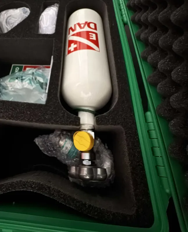 Bouteille de plongée blanche avec détendeur et logo DAN dans un coffre