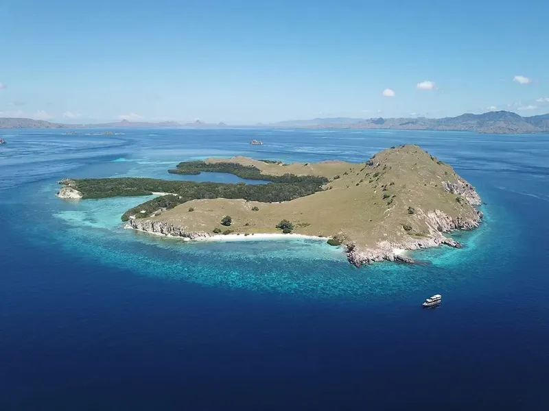 Île tropicale avec plage, eau turquoise et un bateau en mer
