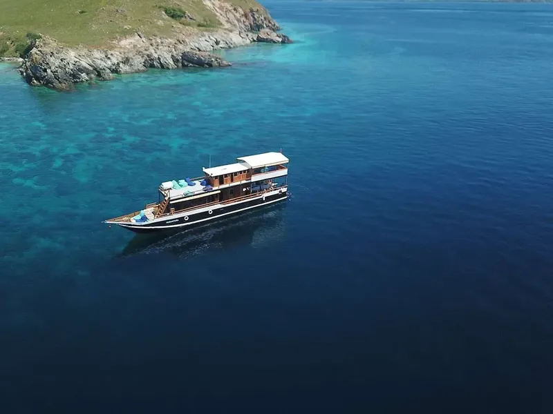 Bateau de plongée naviguant dans une eau turquoise près d'une côte rocheuse