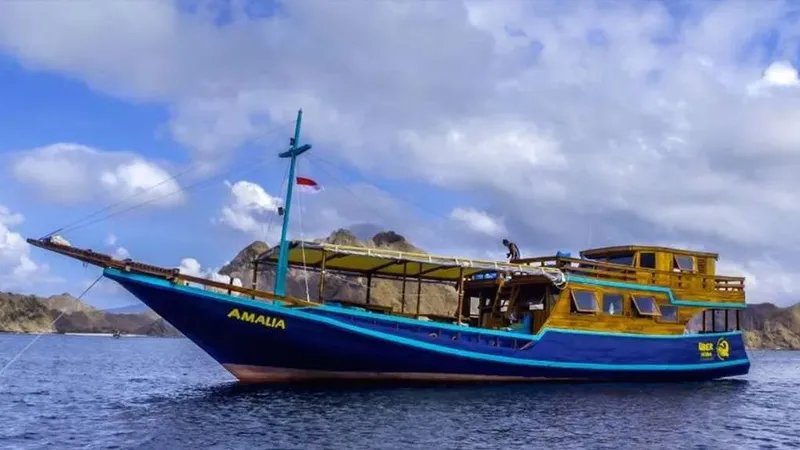 Bateau de plongée bleu et bois, personnes à bord, ciel nuageux