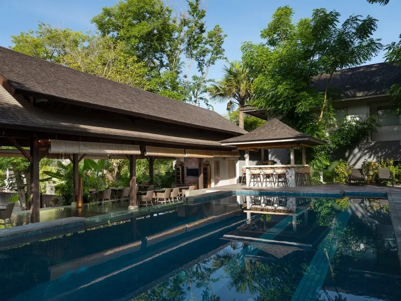 Bâtiments avec toits en pente, piscine et végétation tropicale luxuriante