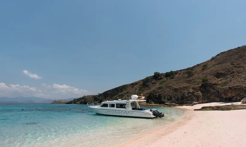Bateau de plongée amarré sur une plage de sable blanc turquoise