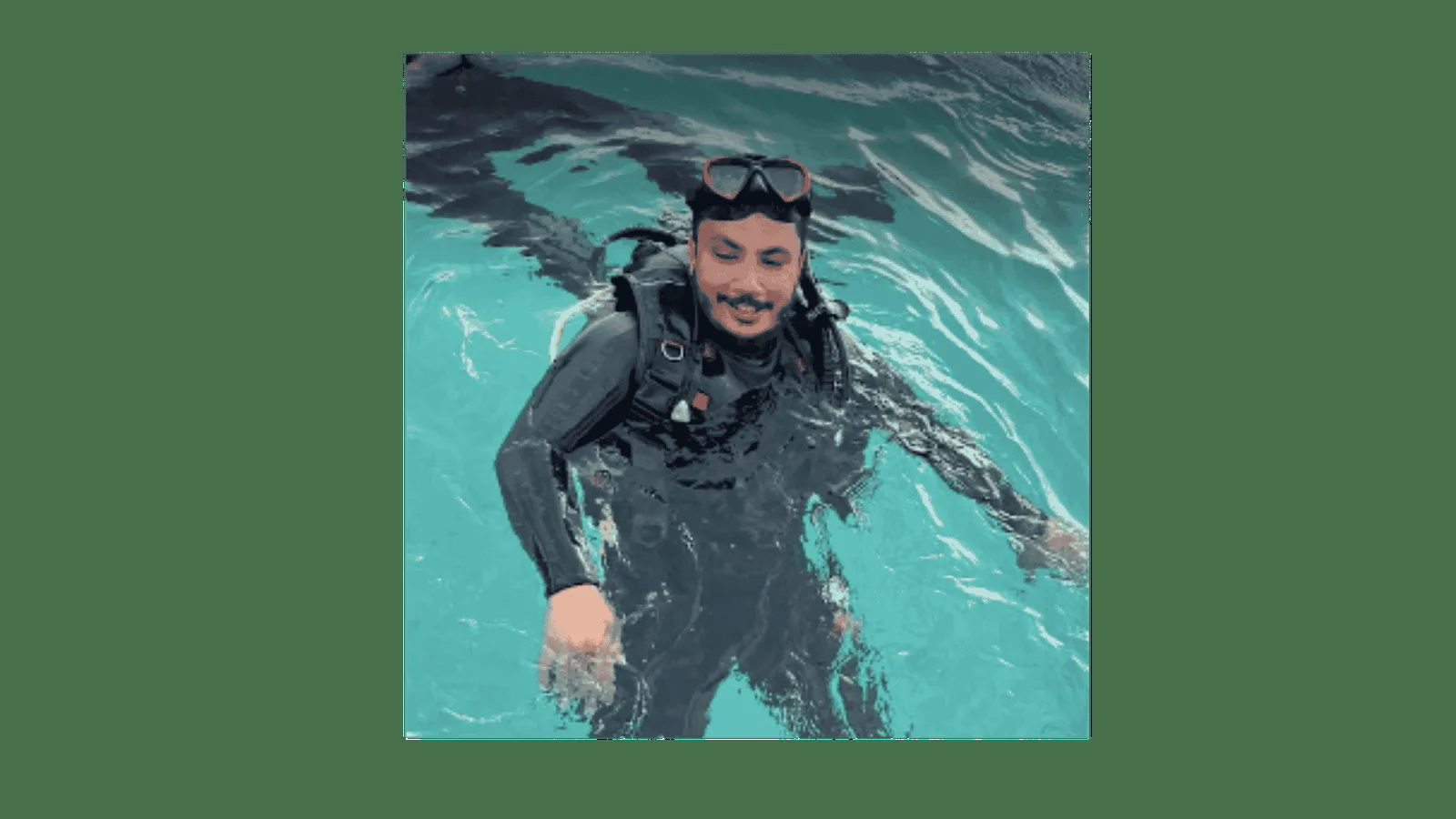 Plongeur souriant en combinaison, lunettes et gilet, dans l'eau turquoise