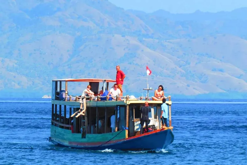 Bateau de plongée avec des passagers en mer, paysage montagneux en arrière-plan