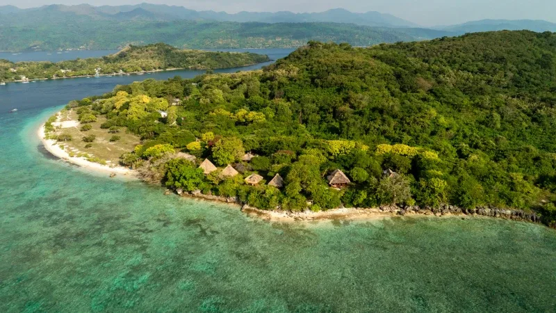 Vue aérienne d'une île tropicale avec des bungalows et végétation luxuriante