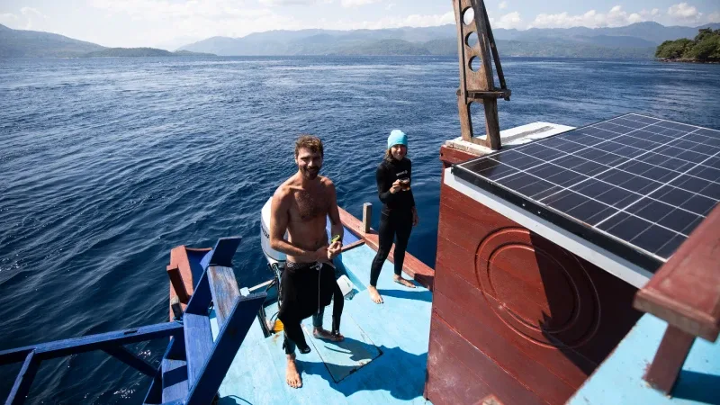 Deux plongeurs souriants sur le pont d'un bateau en mer