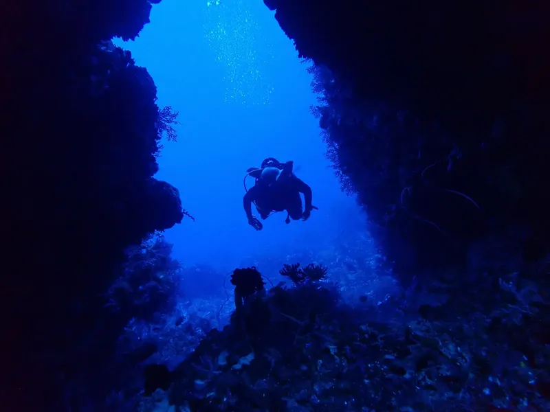 Plongeur silhouette dans une grotte sous-marine, lumière bleue, exploration