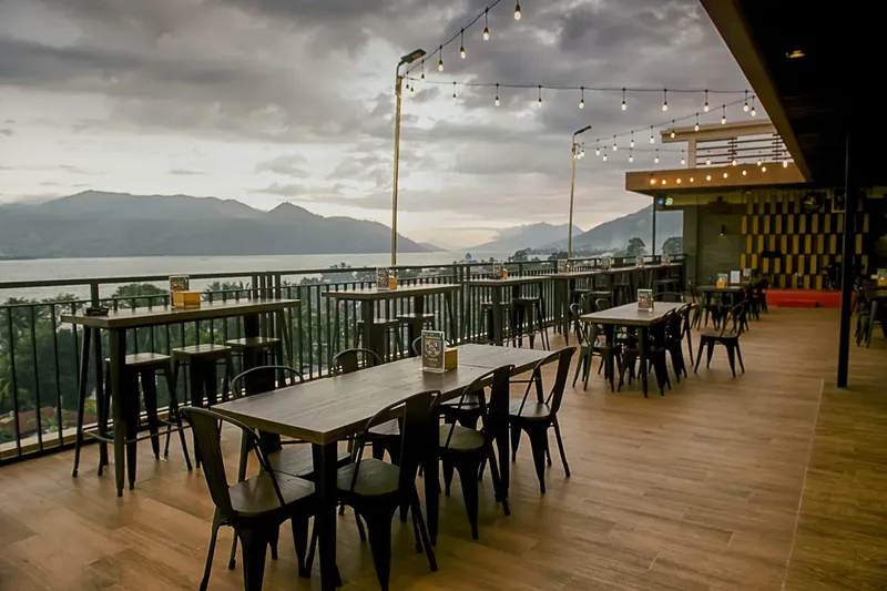 Terrasse aménagée avec tables, chaises et vue sur mer et montagnes