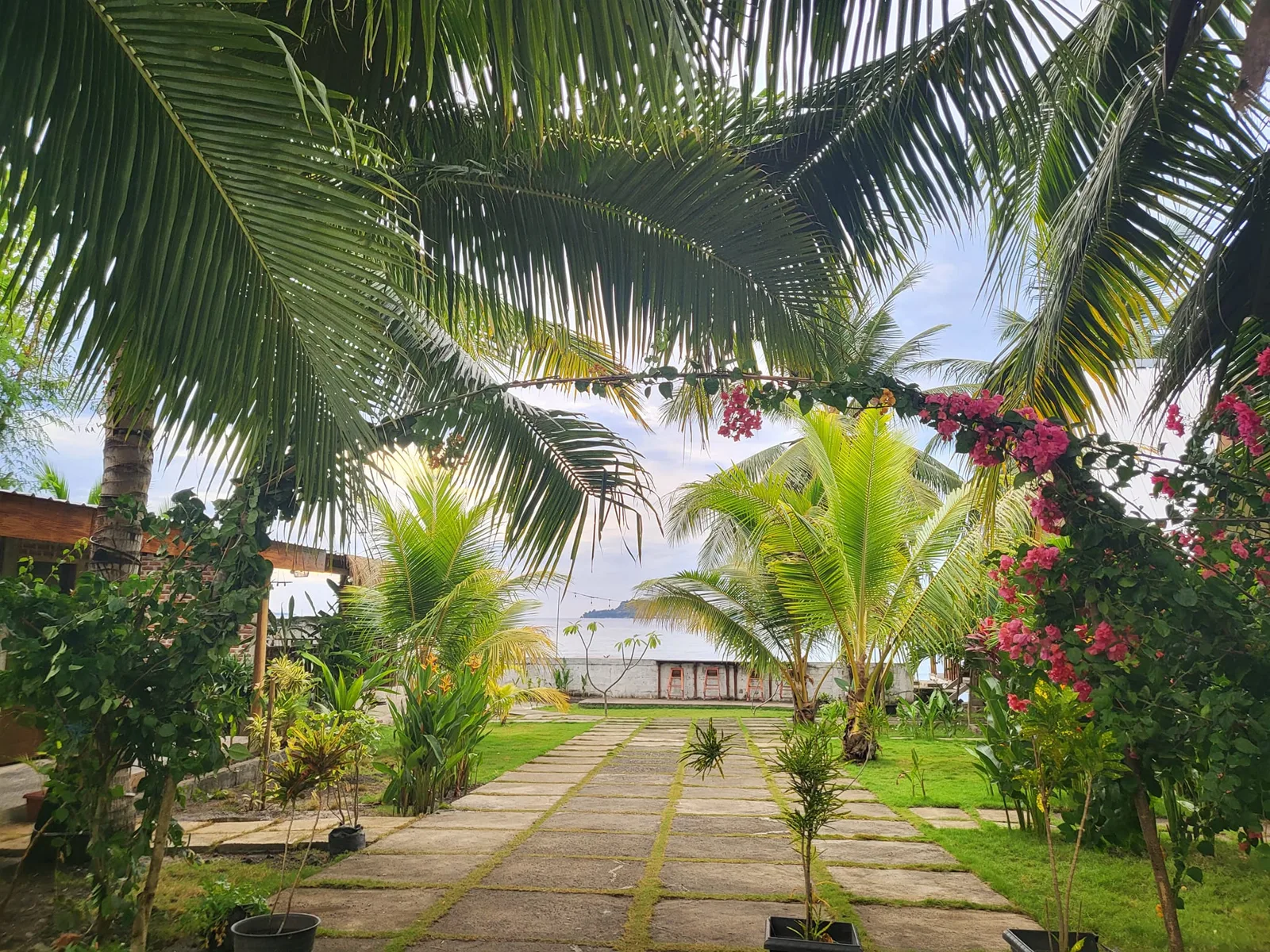 Jardin tropical avec allée menant à la mer et bateaux