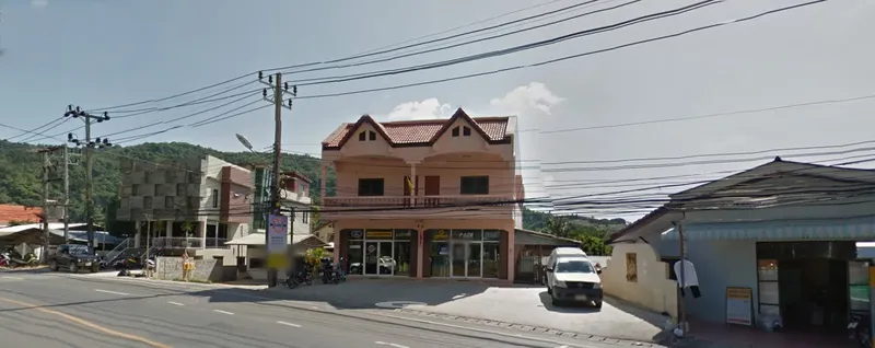 Façade d'un bâtiment rose avec des commerces et une route passante
