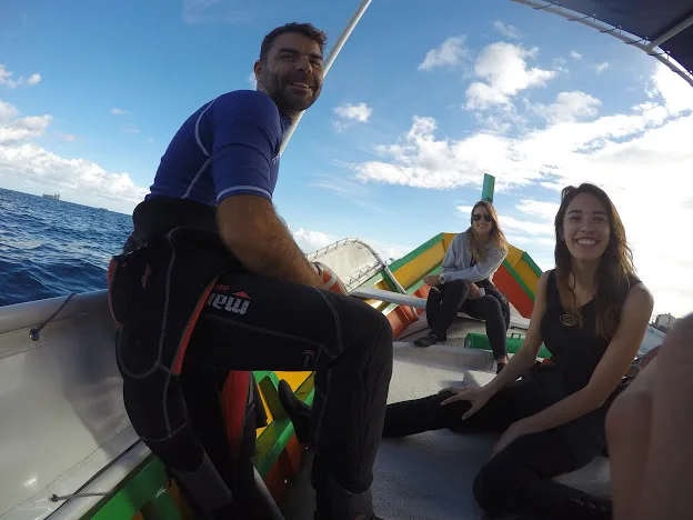 Trois personnes souriantes à bord d'un bateau de plongée en mer